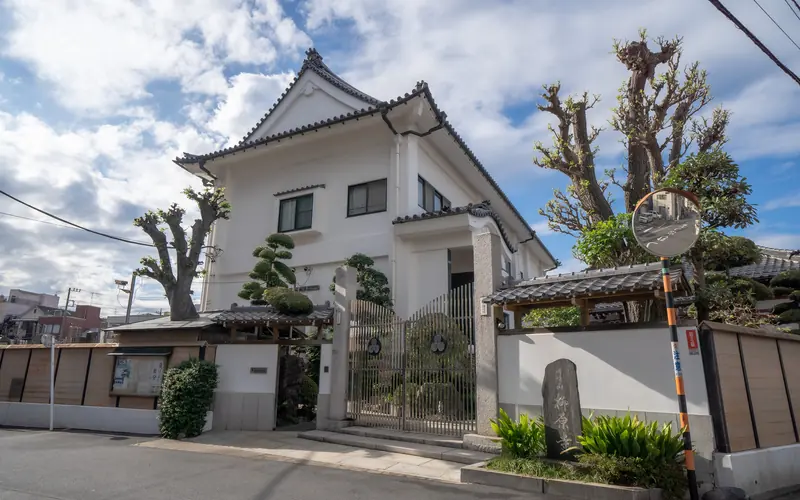 理性院会館の建物の外観（門と庭木）