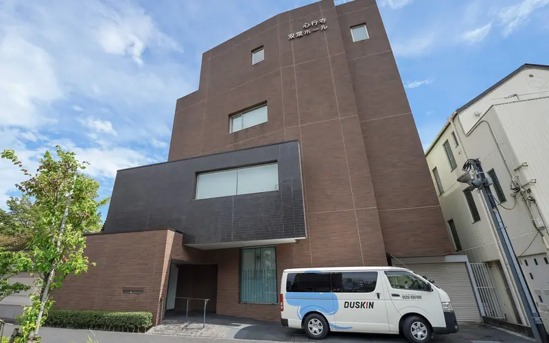 心行寺双葉ホールの建物の外観(車両と並ぶ)